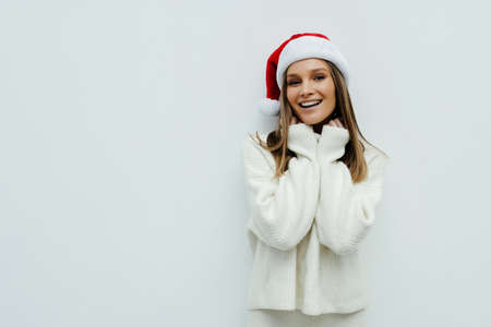 portrait of a smiling beautiful happy woman in christmas santa hat on white background.の写真素材