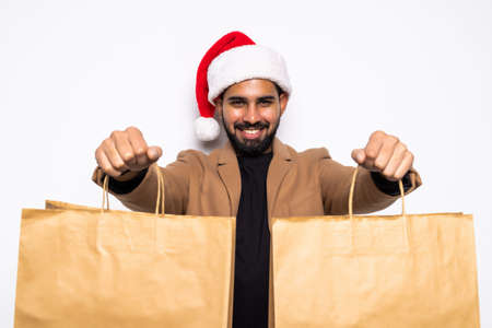 Young sexy man in Santa Claus hat with shopping bags isolated on whiteの写真素材