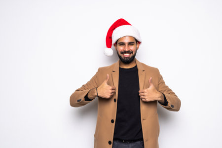 Young handsome man in business suit and Santa hats on white background showing thumbs upの写真素材