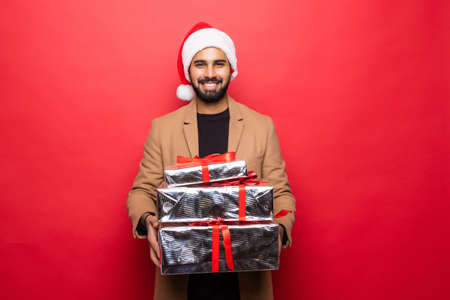 Young man carries a lot of presents, isolated on redの写真素材