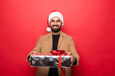 Young man carries a lot of presents, isolated on redの写真素材