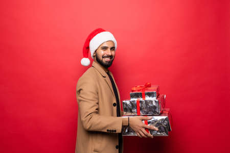 Handsome romantic guy is looking at camera and smiling on red backgroundの写真素材