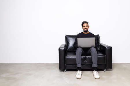 Handsome young man using his laptop in bright living roomの写真素材