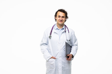 portrait of a male doctor holding laptop computer and looking at camera isolated on a white backgroundの写真素材