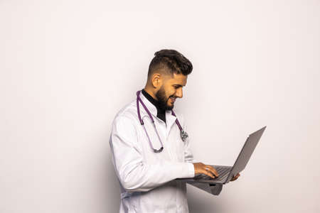 Young middle east doctor standing with Stethoscope and laptop isolated on white backgroundの写真素材