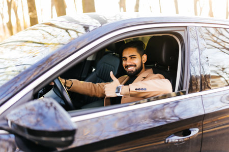 Young asian man smiling and showing thumb up in his car.の写真素材