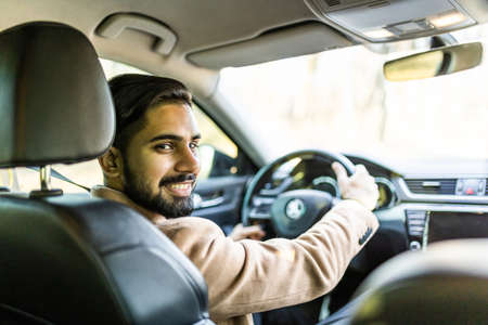 Success in motion. Handsome young man in full suit smiling while driving a carの写真素材