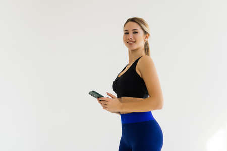 Two fitness women using smartphone while resting after working out in a gym.の写真素材