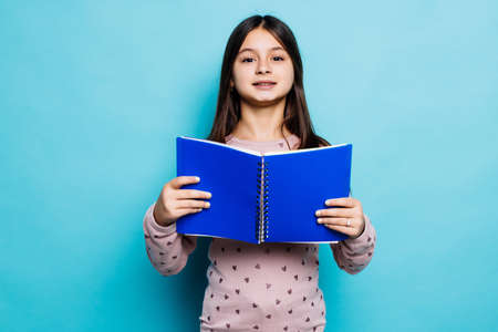 happy teen girl make notes on blue background, knowledge