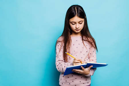 Cheerful teen student girl hold books isolated on pastel blue background studio portraitの写真素材