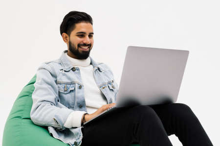 Young man smiling beaming enjoying finishing his project isolated over gray color background