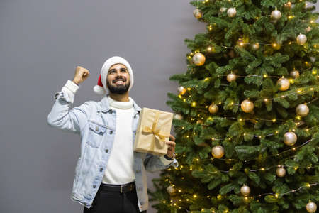 Smiling young excited man opening Christmas gift at homeの写真素材