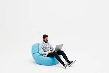 Young man holding notebook browsing chatting colleagues sitting comfy soft armchair wear specs...