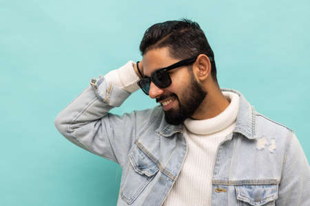 Photo of confident cheerful handsome indian man summer vacation wear sunglass green hoodie isolated teal color backgroundの写真素材