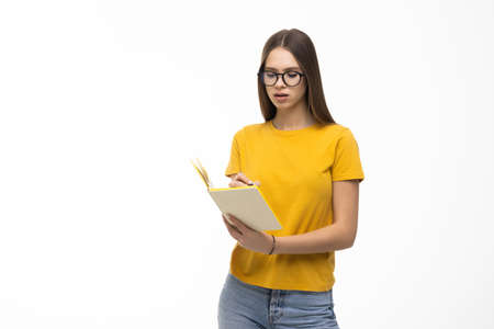 Young student holding colorful books in her arm on white background.