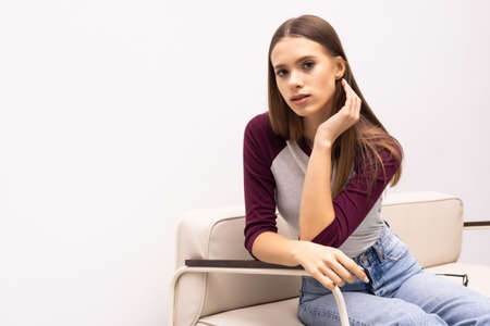 Young woman sitting on her white sofa at home