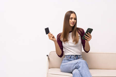 Portrait beautiful young woman use mobile phone or laptop with credit card on sofa in living room...
