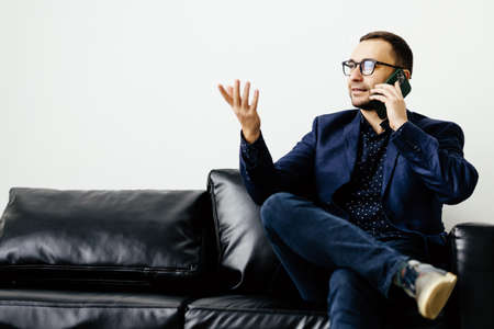 business man talking on the phone sitting on sofaの写真素材