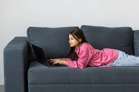Cute girl sitting on sofa with laptopの写真素材