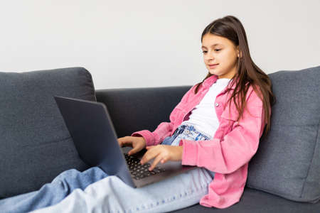 Little girl surfs on the internet sitting on the sofaの写真素材