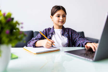 Photo of positive kid girl study remote sit desk table use laptop have online communication lesson...