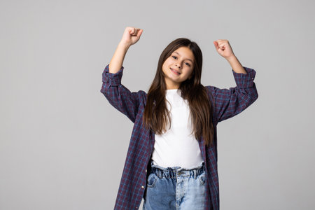 young schoolgirl happy positive with smile rejoices in victory fists hands isolated on gray backgroundの写真素材