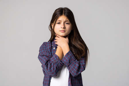 Little girl suffering from sore throat on gray backgroundの写真素材