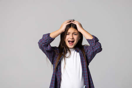 Close up portrait with little brown-haired girl. Concept happy activity playful kid speaks loudly with closing eyes on gray background, six year child have a good time and posing.の写真素材
