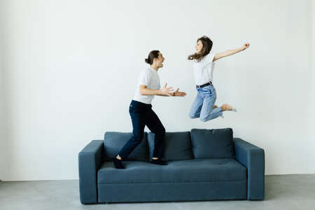 Happy young couple in love having fun together jumping on the sofa in the living room at home....
