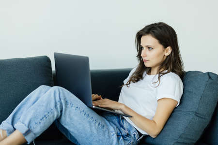 Woman using a laptop while relaxing on the couch