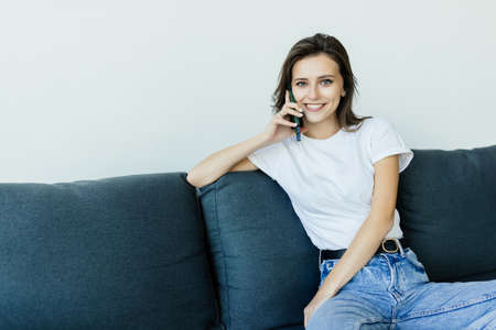 Happy young woman caller talking on the phone at home, cheerful teen girl enjoys pleasant mobile...