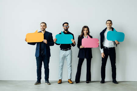 Beautiful young people are holding speech bubbles, looking at camera and smiling isolated on white backgroundの写真素材