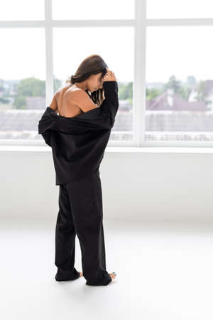 Young business woman with stretched black jacket from under which black bra is visible standing isolated on white background.の写真素材