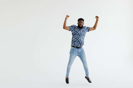 Full length portrait of a cheerful afro american man in headphones jumping isolated on a white backgroundの写真素材