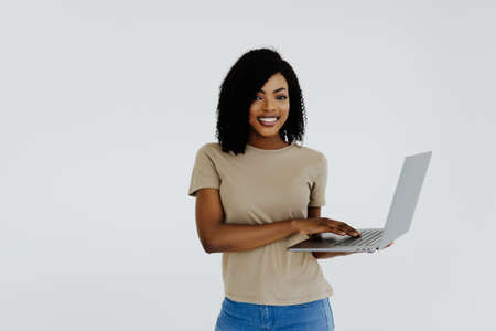Portrait of happy young afro american woman using laptop computer isolated over whiteの写真素材