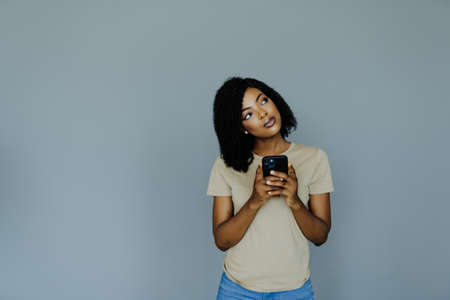 Portrait African American woman using phone isolated on gray backgroundの写真素材