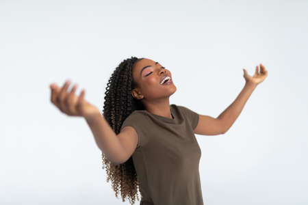 Beautiful young black woman celebrates with her hands in the air on white backgroundの写真素材