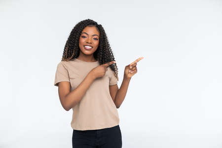 Portrait of happy black girl with afro pointing fingers at copy spaceの写真素材