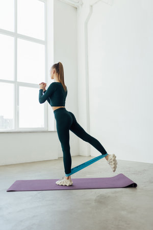 Woman during her fitness workout at home with rubber resistance band