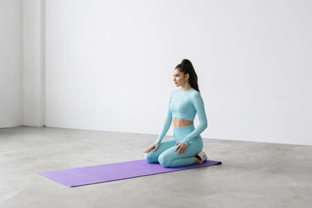 Shot of fitness woman sitting on exercise mat at rest