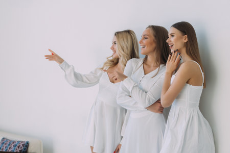Pleased three women smiling pointed side over white wallの写真素材