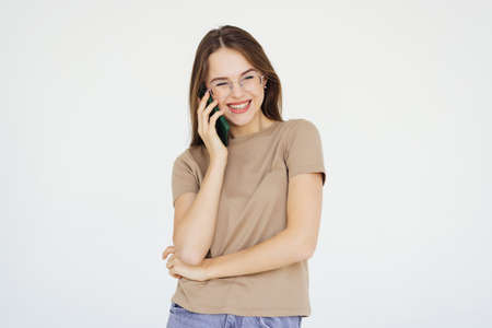 Portrait of a smiling young woman talking on mobile phone over white background