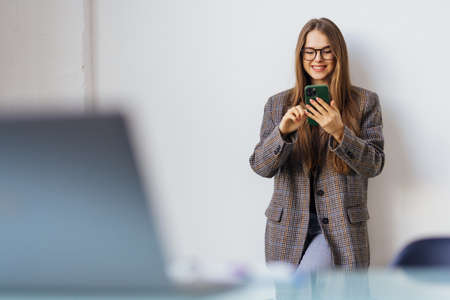 Charming woman with a smile standing phone at the office.の写真素材