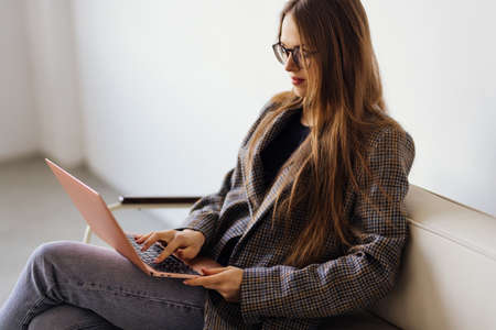 Woman using a laptop while relaxing on the couchの写真素材