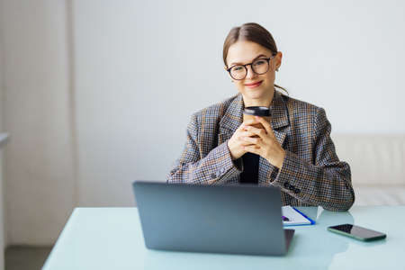 Young business woman sitting at table and taking notes in notebook.の写真素材