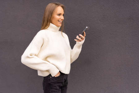 Young stylish woman using phone walking on the street