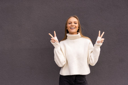 Cool woman shows peace sign, show tongue, close eyes and posing outside.の写真素材
