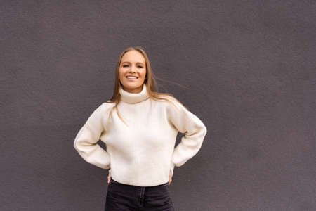 Young woman standing on the street on gray wallの写真素材