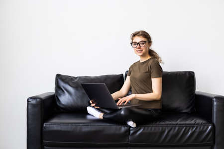 Woman using a laptop while relaxing on the couchの写真素材