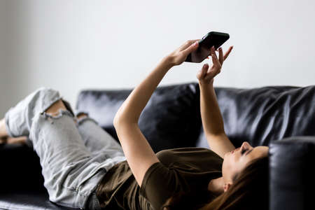 Portrait beautiful woman use smart mobile phone on sofa in living room interiorの写真素材